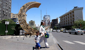 An Iranian woman holds her son's school bag as she leads him towards a busy street in the capital Tehran on May 9, 2026. (AFP)