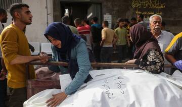 Palestinians mourn by bodies of relatives killed in Israeli strikes, at Al-Shifa hospital in Gaza City on May 18, 2025. (AFP)